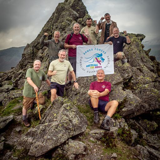 Veterans on a mountain summit holding the Battling the Odds flag